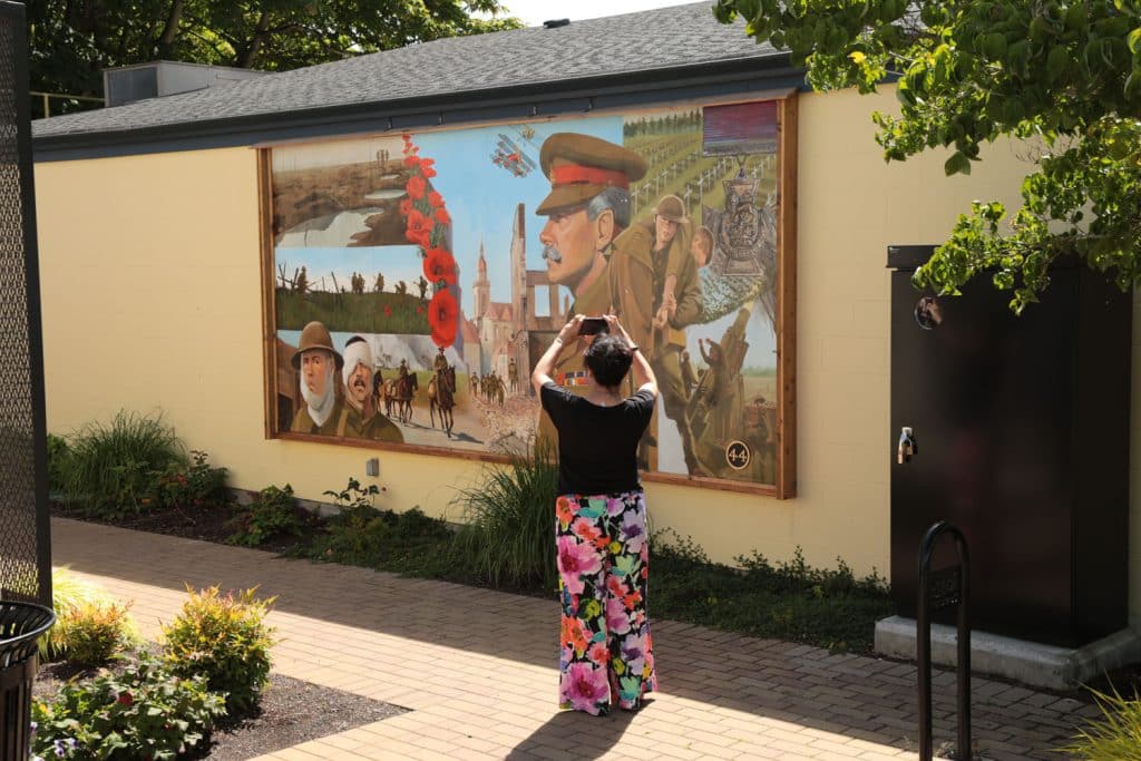 Person photographing a colorful mural.