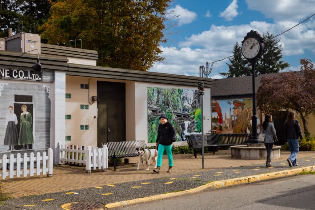 People walking near mural and clock.