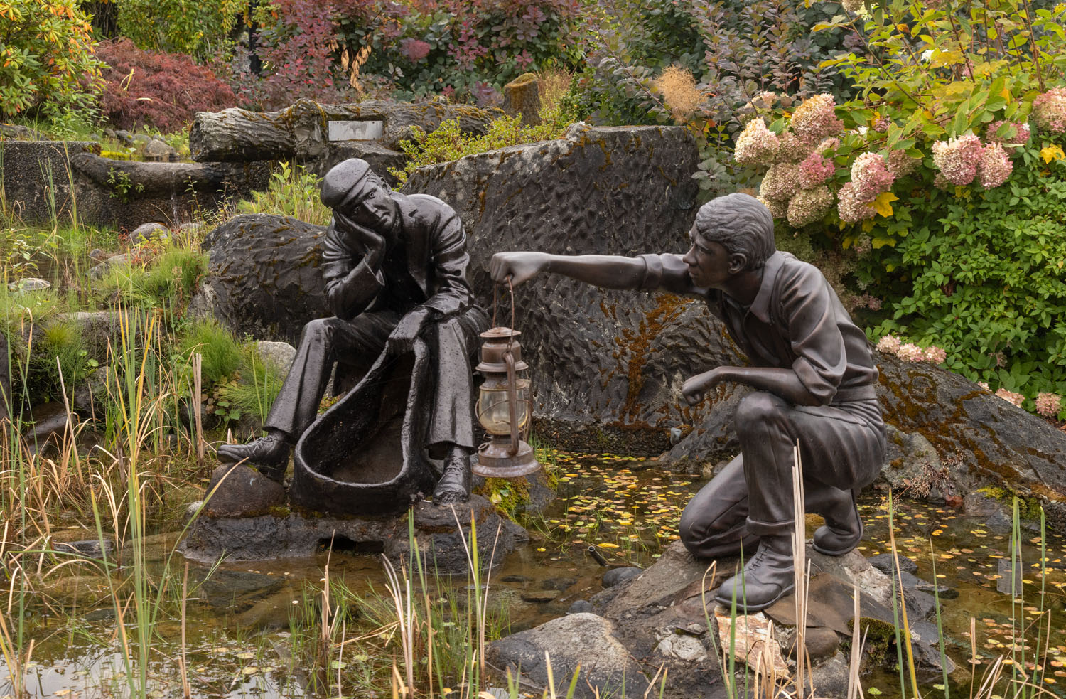 Two bronze figures by a pond.