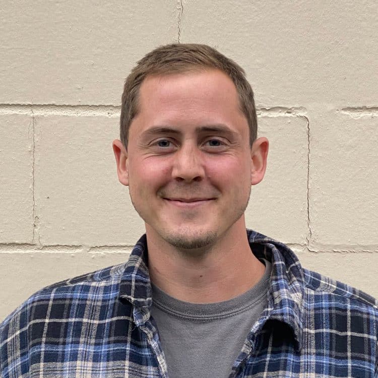 Man wearing plaid shirt, gray background.