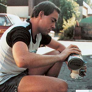 Person sitting with cans outdoors.