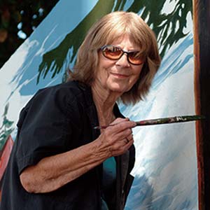 Artist painting a mural outdoors.
