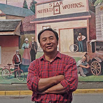 Man posing in front of mural.